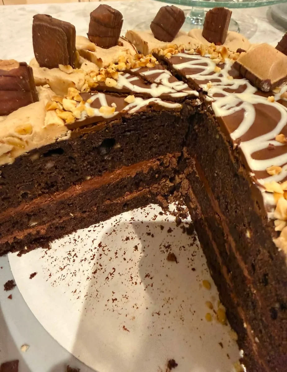 Rich homemade chocolate cake decorated with chocolate pieces, sliced on a cake stand