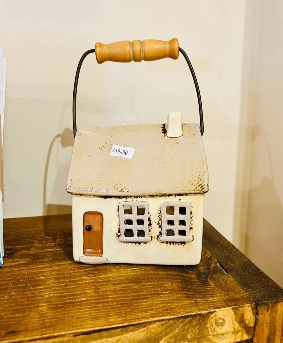 A ceramic house-shaped lantern on a wooden table