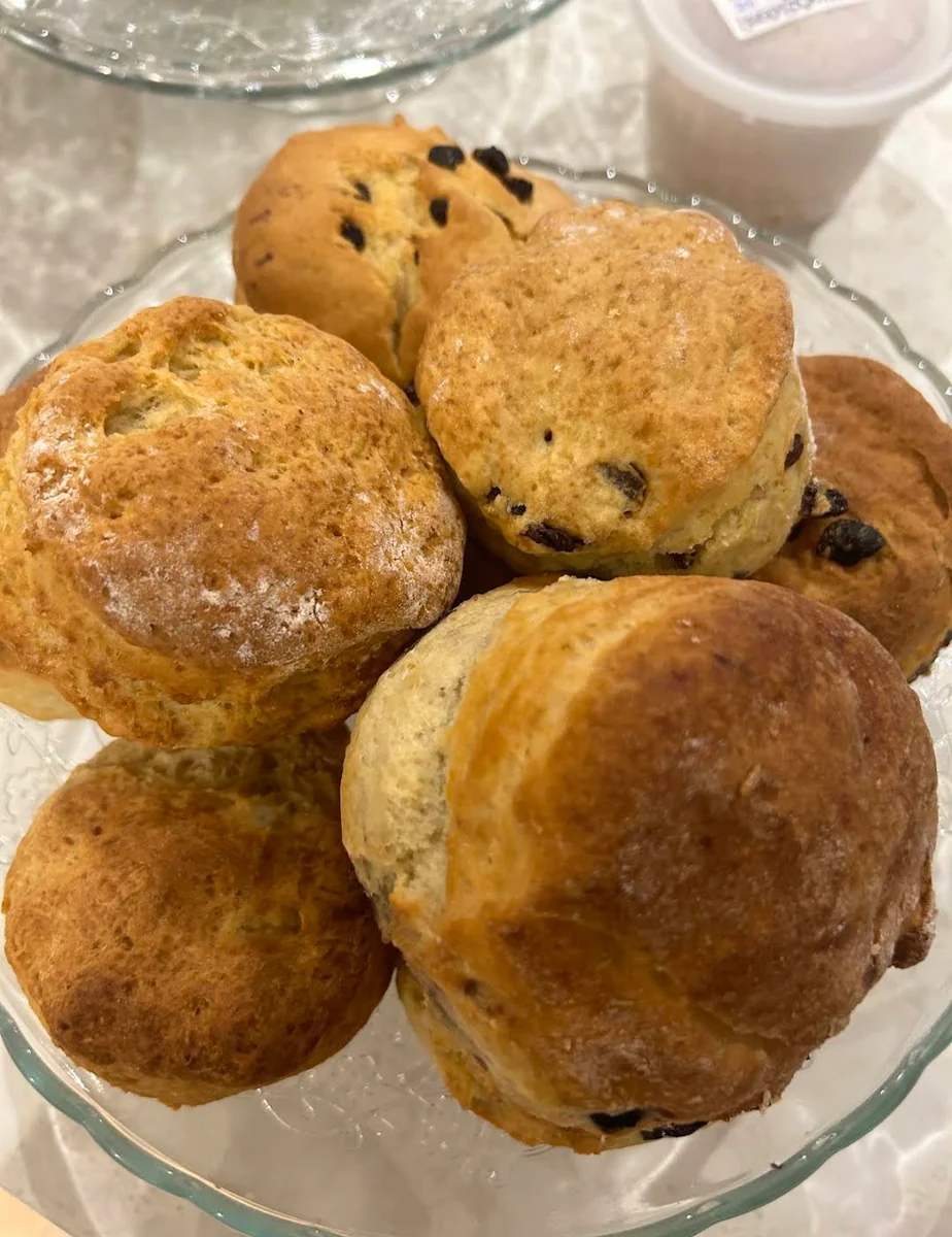 Freshly baked fruit scones piled on a glass stand